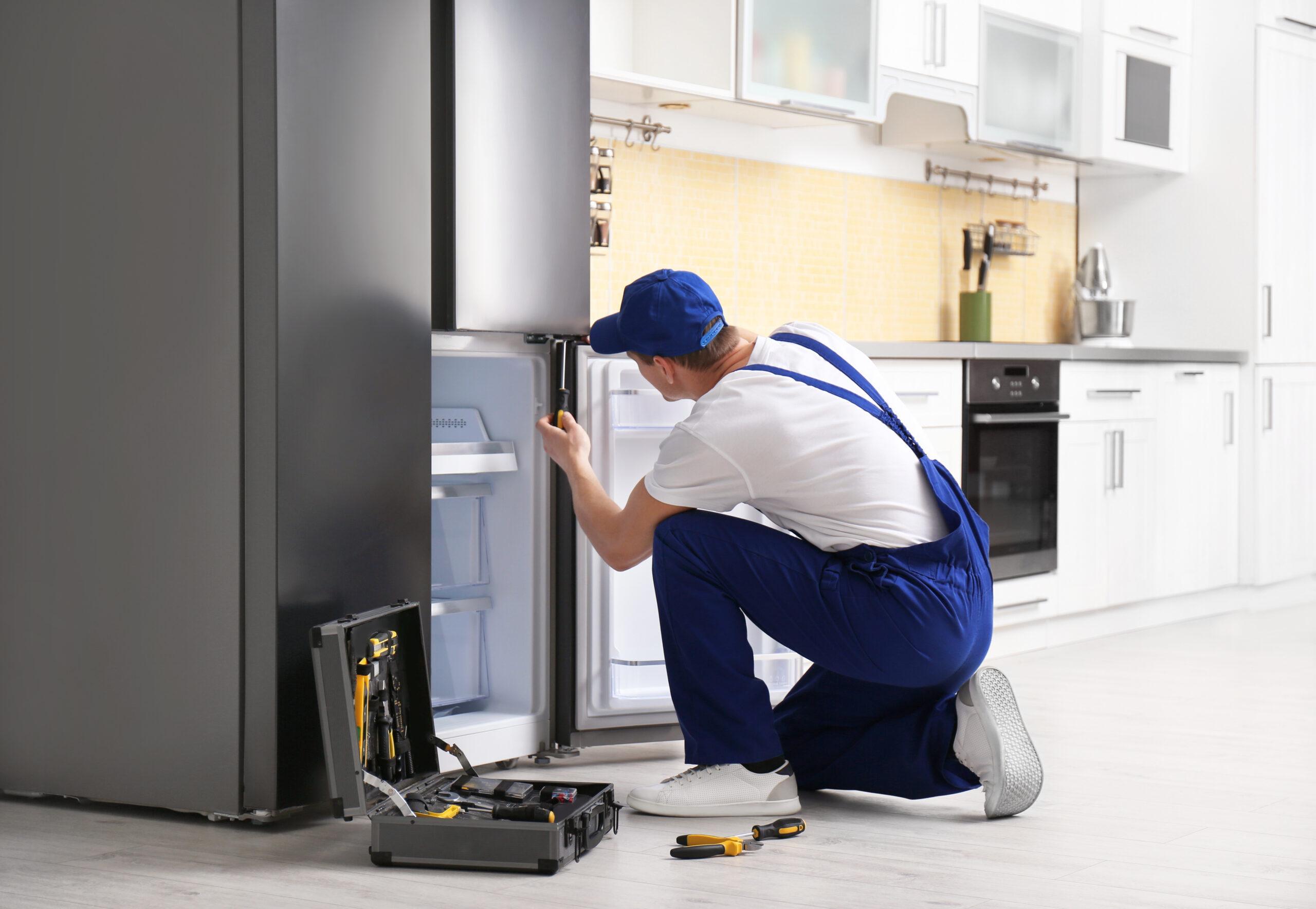 Appliance repair tech fixing the fridge